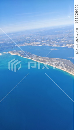 Aerial view of a coastal landscape featuring sandy beaches and turquoise waters, with a peninsula extending into the ocean under a clear blue sky Aerial view of a coastal landscape featuring sandy beaches and turquoise waters, with a peninsula extending into the ocean under a clear blue sky 141326602