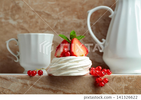 Pavlova dessert with strawberries, red currant, and mint on a beige table. Pavlova dessert with strawberries, red currant, and mint on a beige table. 141326622