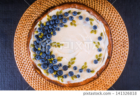 Fresh cake with blueberries, seeds on woven plate at kitchen table Fresh cake with blueberries, seeds on woven plate at kitchen table 141326818