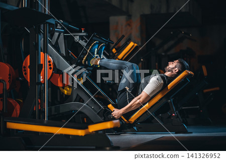 young man has legs workout in modern gym young man has legs workout in modern gym 141326952