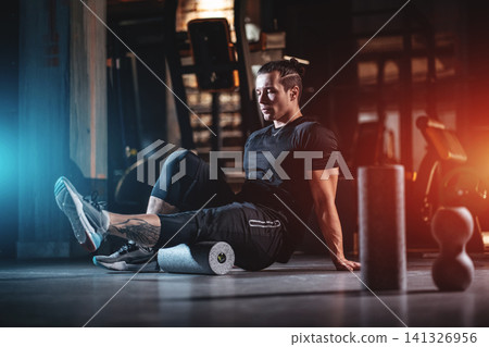 young man has crossfit workout with myofascial roller and weight in gym young man has crossfit workout with myofascial roller and weight in gym 141326956