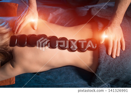 masseur making healing stone massage for womans spine masseur making healing stone massage for womans spine 141326991