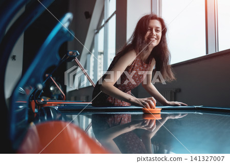 beautiful brunette female playing air hockey with friend beautiful brunette female playing air hockey with friend 141327007