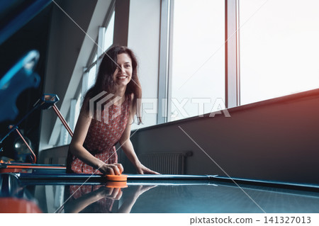 beautiful brunette female playing air hockey with friend beautiful brunette female playing air hockey with friend 141327013