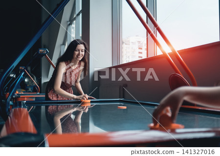 beautiful brunette female playing air hockey with friend beautiful brunette female playing air hockey with friend 141327016