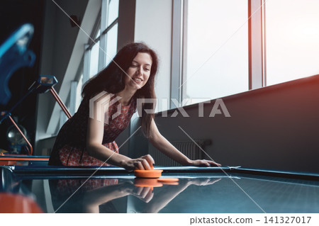 beautiful brunette female playing air hockey with friend beautiful brunette female playing air hockey with friend 141327017