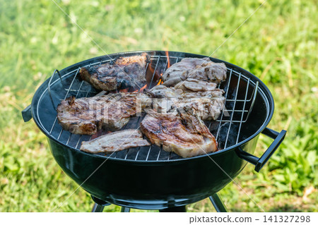 Delicious barbecue of grilled meat and vegetables and a family in the blurred background in spring outdoors. Delicious barbecue of grilled meat and vegetables and a family in the blurred background in spring outdoors. 141327298