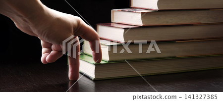 Hand walking on a ladder made of books Hand walking on a ladder made of books 141327385