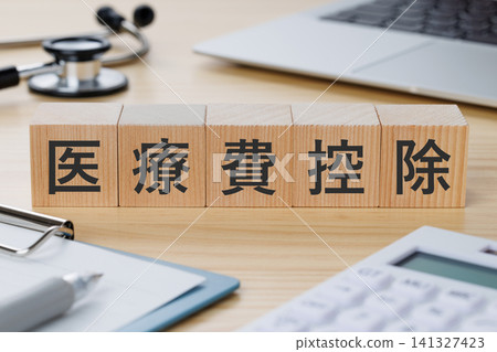 A stack of building blocks on a desk with "Medical Expense Deduction" written on it (medical imagery). A stack of building blocks on a desk with "Medical Expense Deduction" written on it (medical imagery). 141327423