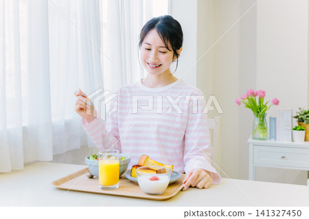 Young woman eating breakfast at home Young woman eating breakfast at home 141327450