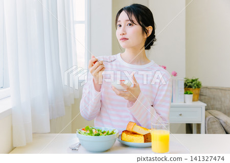 Young woman eating breakfast at home Young woman eating breakfast at home 141327474