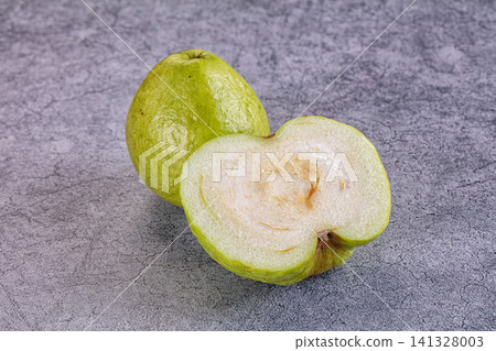 Fresh green guava whole and sliced on textured gray surface Fresh green guava whole and sliced on textured gray surface 141328003