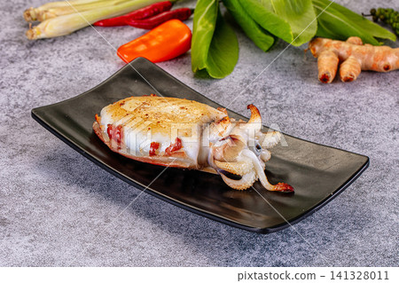 Grilled squid on black plate with fresh herbs and spices Grilled squid on black plate with fresh herbs and spices 141328011