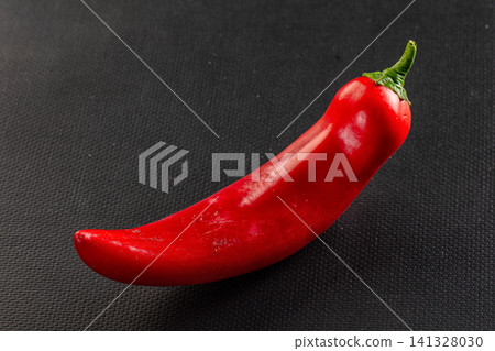 Vibrant red chili pepper on dark textured surface Vibrant red chili pepper on dark textured surface 141328030