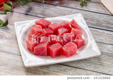 Fresh raw tuna cubes on white plate with rustic wooden background Fresh raw tuna cubes on white plate with rustic wooden background 141328068