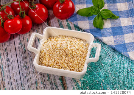 Sesame seeds in white ceramic bowl with cherry tomatoes and basil on rustic wooden table Sesame seeds in white ceramic bowl with cherry tomatoes and basil on rustic wooden table 141328074
