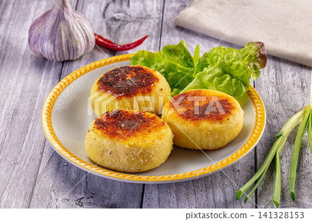 Golden fried cheese cakes with fresh greens and garlic on rustic plate Golden fried cheese cakes with fresh greens and garlic on rustic plate 141328153