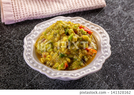 Green vegetable dip in white ceramic bowl on dark stone surface Green vegetable dip in white ceramic bowl on dark stone surface 141328162