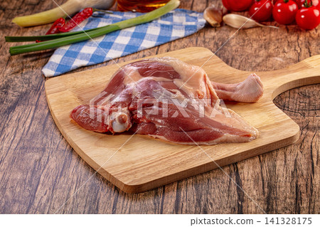 Raw duck leg on wooden cutting board, fresh ingredients for cooking, rustic kitchen setting, gourmet cuisine preparation Raw duck leg on wooden cutting board, fresh ingredients for cooking, rustic kitchen setting, gourmet cuisine preparation 141328175