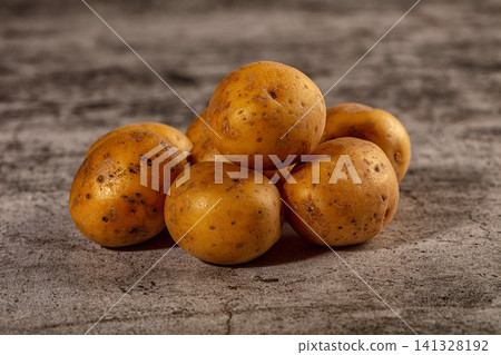 Fresh golden potatoes piled on rustic concrete surface Fresh golden potatoes piled on rustic concrete surface 141328192