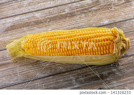 Fresh yellow corn on cob with husk on rustic wooden background Fresh yellow corn on cob with husk on rustic wooden background 141328233