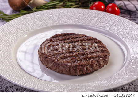 Grilled beef patty on white plate with rosemary and cherry tomatoes Grilled beef patty on white plate with rosemary and cherry tomatoes 141328247