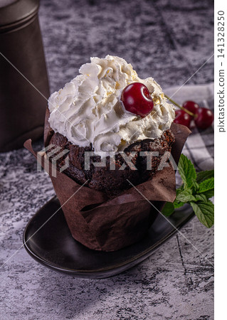 Chocolate cupcake with whipped cream and cherry on dark plate Chocolate cupcake with whipped cream and cherry on dark plate 141328250