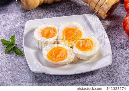 Four soft boiled egg halves on white plate with basil and wooden pepper mill Four soft boiled egg halves on white plate with basil and wooden pepper mill 141328274