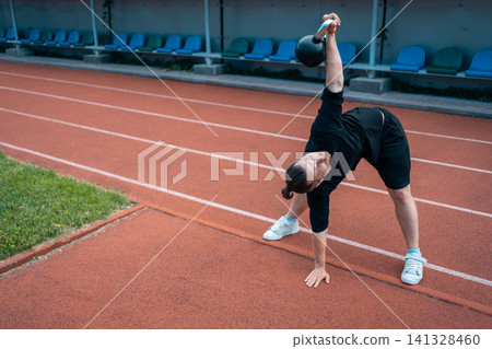 young athlete has workout and doing sport exercises with kettlebell outdoor young athlete has workout and doing sport exercises with kettlebell outdoor 141328460