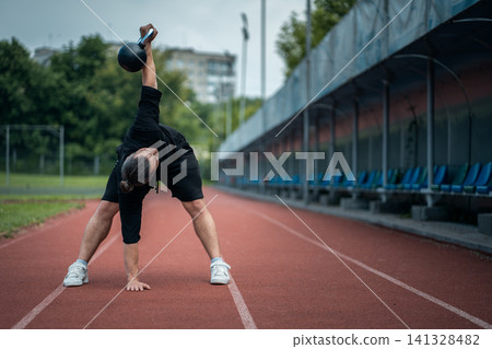 young athlete has workout and doing sport exercises with kettlebell outdoor young athlete has workout and doing sport exercises with kettlebell outdoor 141328482