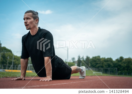 athletic sportsman has workout or planking and stretching outdoor athletic sportsman has workout or planking and stretching outdoor 141328494
