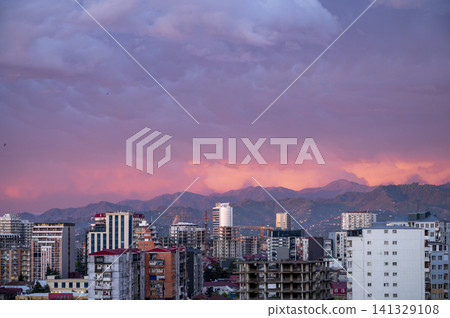 City skyline with mountains at sunset in warm colorful evening light. 141329108