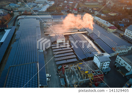 Aerial view of solar power plant with blue photovoltaic panels mounted on industrial building roof for producing green ecological electricity. Production of sustainable energy concept Aerial view of solar power plant with blue photovoltaic panels mounted on industrial building roof for producing green ecological electricity. Production of sustainable energy concept 141329405