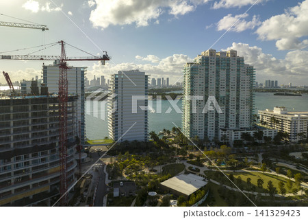 Aerial view of new developing residense in american urban area. Tower cranes at industrial construction site in Miami, Florida. Concept of housing growth in the USA Aerial view of new developing residense in american urban area. Tower cranes at industrial construction site in Miami, Florida. Concept of housing growth in the USA 141329423