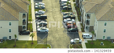 Aerial view of cars parked on parking places at american apartment building in Florida residential area. New family condos as example of housing development in US suburbs Aerial view of cars parked on parking places at american apartment building in Florida residential area. New family condos as example of housing development in US suburbs 141329459