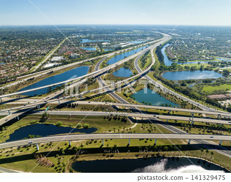 Aerial view of American freeway intersection with fast driving cars and trucks in Miami, Florida. USA city transportation infrastructure Aerial view of American freeway intersection with fast driving cars and trucks in Miami, Florida. USA city transportation infrastructure 141329475