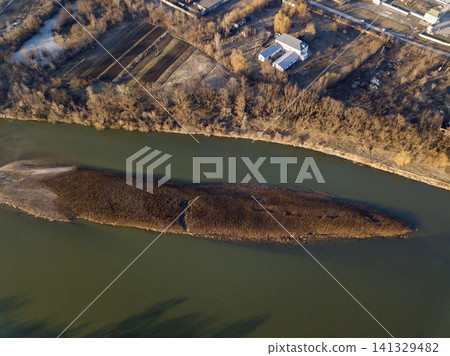 Aerial top view, countryside panorama of small island with dry grass in quiet river on sunny day. Drone photography. Aerial top view, countryside panorama of small island with dry grass in quiet river on sunny day. Drone photography. 141329482