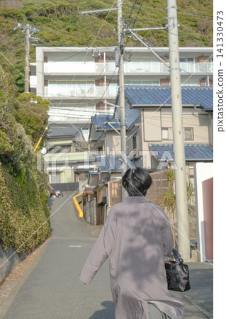 A figure walking up a hill and a quiet afternoon in a residential area. A figure walking up a hill and a quiet afternoon in a residential area. 141330473