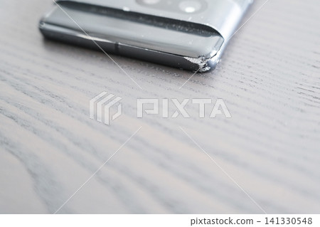 A smartphone with a chipped corner on the desk A smartphone with a chipped corner on the desk 141330548