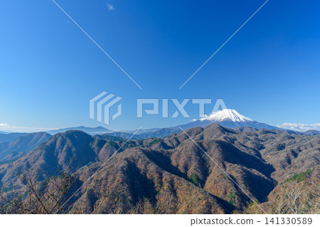 A beautiful view of snow-covered Mount Fuji and the surrounding mountain range from near Mount Omuro in the western Tanzawa Mountains on a clear winter day. 141330589