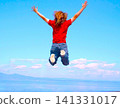 The back view of an American man leaping into the air against a blue sky. 141331017