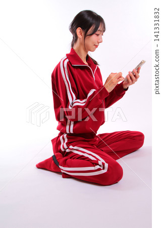 一位身穿運動服的女子正在使用智慧型手機 一位身穿運動服的女子正在使用智慧型手機 141331832