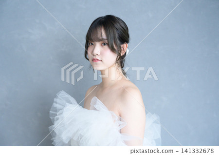 身穿婚紗的日本女子手捧花束，背景是灰色。 141332678
