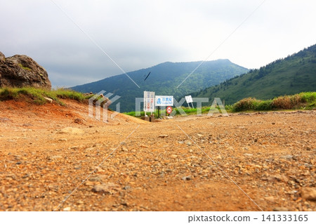 A Gunma Prefecture sign at Kenashi Pass and a radio-controlled airplane soaring through the sky against a mountainous landscape. A Gunma Prefecture sign at Kenashi Pass and a radio-controlled airplane soaring through the sky against a mountainous landscape. 141333165
