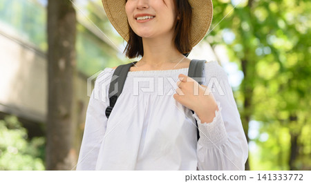 一位戴著草帽的女士在公園裡漫步。 141333772