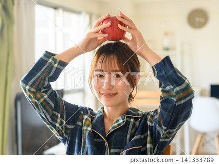 清晨的自然光線下,一位身穿睡衣的女子頭頂著一個蘋果。 清晨的自然光線下,一位身穿睡衣的女子頭頂著一個蘋果。 141333789