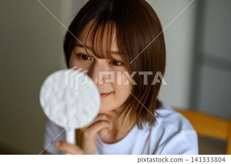 一個女人在鏡子裡檢查她的皮膚 141333804