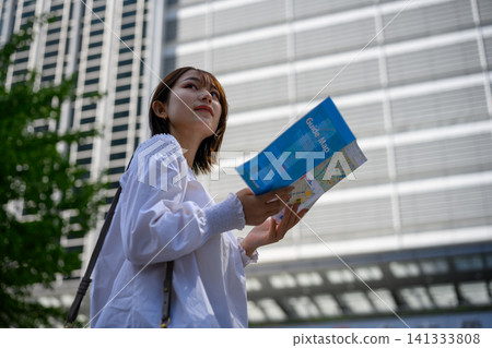 A woman with a guidebook, tourists strolling through the city. A woman with a guidebook, tourists strolling through the city. 141333808