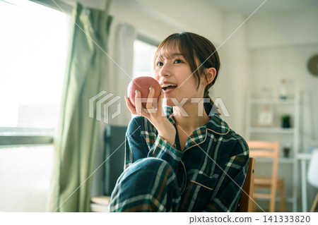 一個穿著睡衣的女人在房間裡吃蘋果。吃蘋果。吃蘋果。 一個穿著睡衣的女人在房間裡吃蘋果。吃蘋果。吃蘋果。 141333820