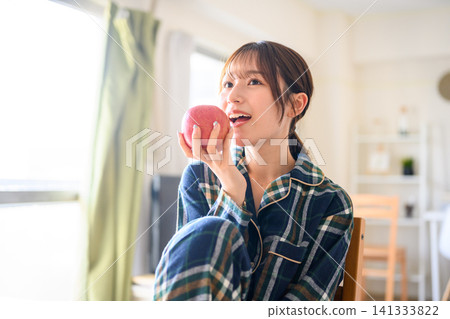 A woman in pajamas eats an apple in her room. Eating an apple. Eating an apple. A woman in pajamas eats an apple in her room. Eating an apple. Eating an apple. 141333822